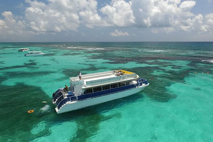 Tour boat anchored in a colorful reef area with clear shallow water.
